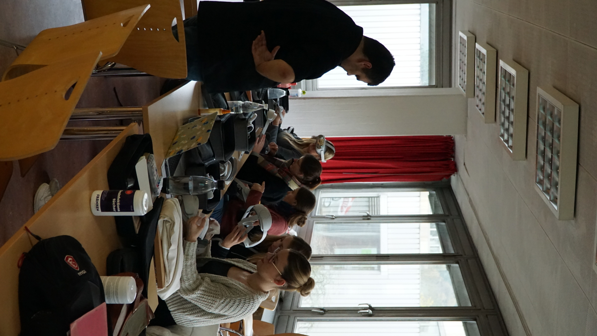 Ramin Siegmund steht vor 5 sitzenden Studierenden, die VR-Headsets in den Händen halten.