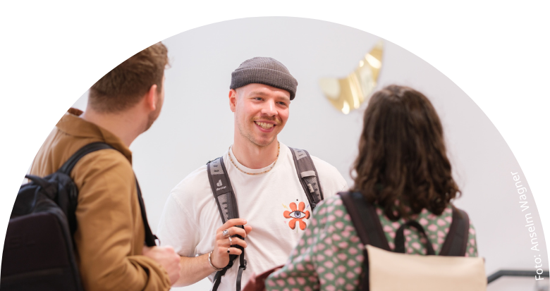 3 sich unterhaltende Studierende in der Universitätsbibliothek Marburg